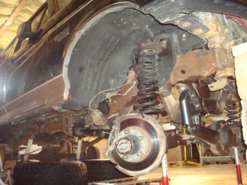 1995 Ford Bronco - The front suspension and wheel well of a Ford Bronco are shown disassembled for maintenance.