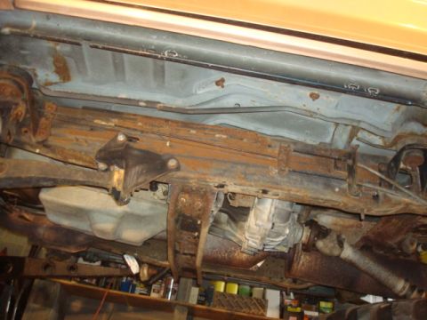1995 Ford Bronco - The underside of a vehicle shows significant rust on its frame, fuel tank, and exhaust components.
