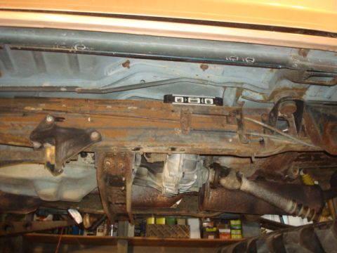 1995 Ford Bronco - The underside of a vehicle, showing the transmission and exhaust components, with a level placed on the frame.