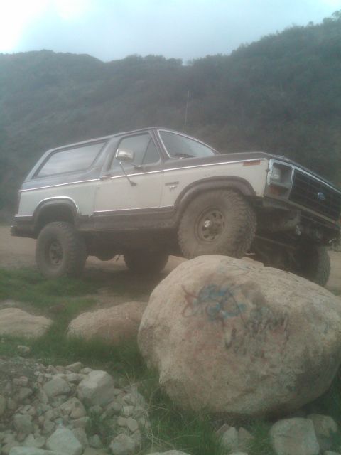 1982 Ford Bronco - This Ford Bronco is navigating rough terrain with one wheel up on a large rock.