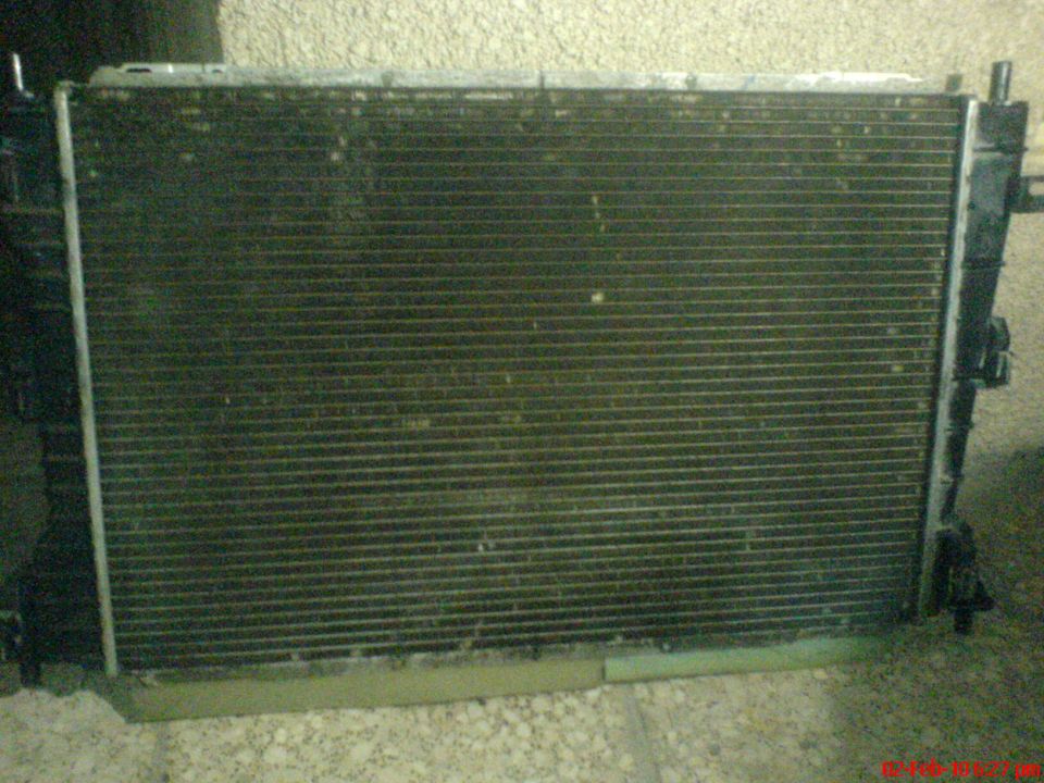 Radiator with visible dirt and debris, part of a vehicle cooling system