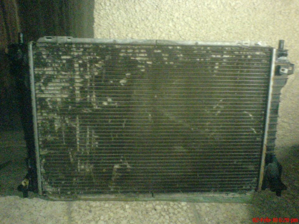 Radiator with visible corrosion and debris. Supermotors.net logo at bottom right