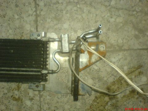 1998 Ford Crown Victoria - A radiator part with attached tubing and wires is shown against a concrete background.