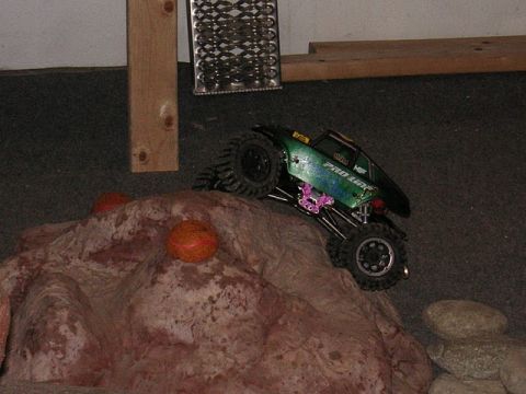 1993 Suzuki Sidekick - A green remote control rock crawler truck navigates a rocky obstacle course, with 'PRO LINE' visible on its side.