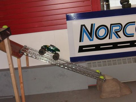 1993 Suzuki Sidekick - A toy monster truck navigates a ramp, with a "NORCO" sign in the background.