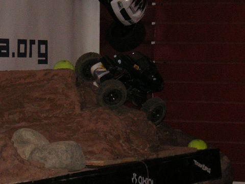 1993 Suzuki Sidekick - A remote control rock crawler navigates a simulated rocky terrain, with a helmet perched nearby.