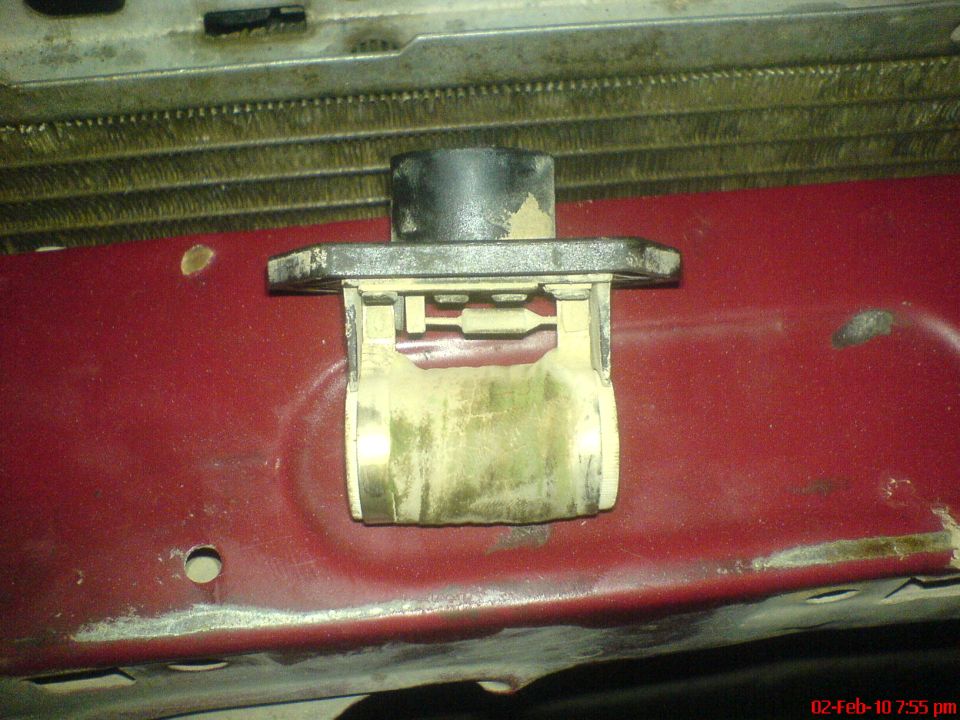 Blower motor resistor part on red metal panel with radiator behind