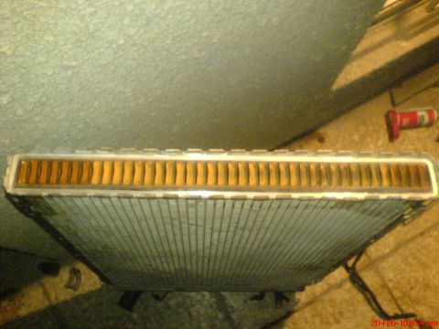 1998 Ford Crown Victoria - Close-up of a vehicle radiator, showing its internal fins and casing. The Supermotors.net watermark is present.