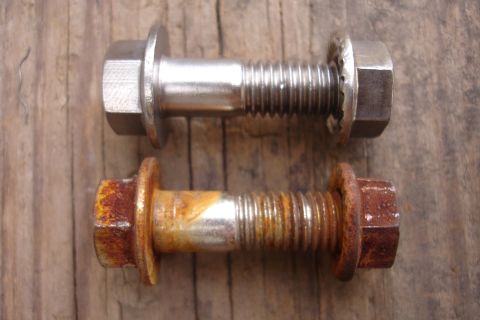 1995 Ford Taurus - Comparison of a new bolt next to a heavily rusted bolt, both on a wooden background.