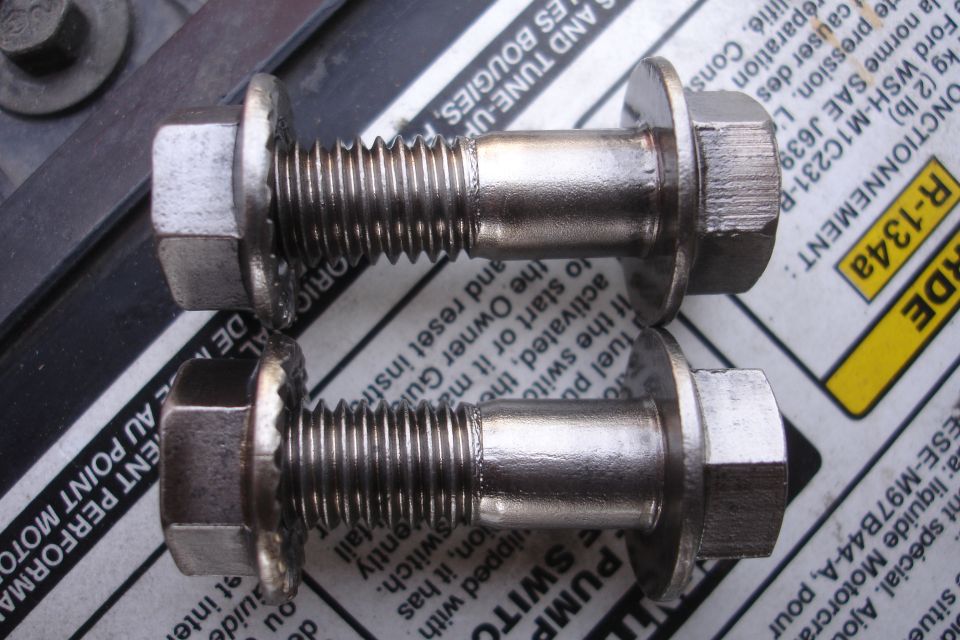 Two threaded metal cam adjuster bolts on a Ford service manual page