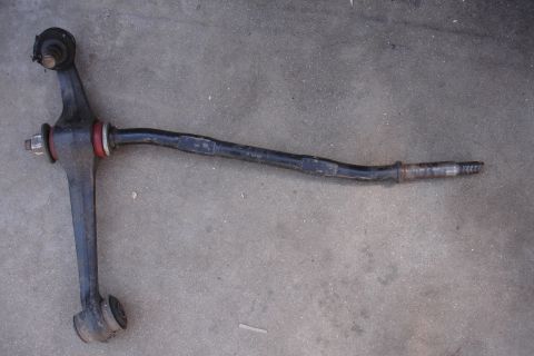1995 Ford Taurus - A single automotive suspension control arm is shown on a concrete surface.