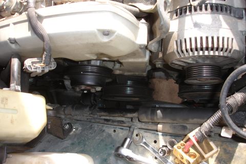 1995 Ford Taurus - Close-up view of engine components including the alternator and multiple drive pulleys, with tools nearby.