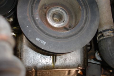 1995 Ford Taurus - Close-up of an engine component, showing a pulley and an oil pan with a leak.