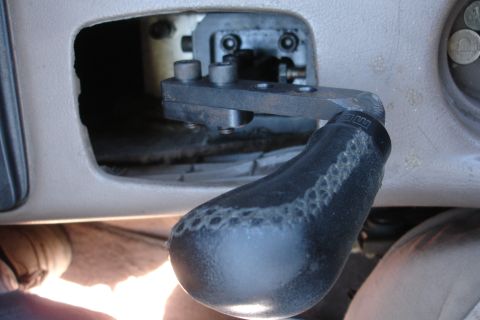 1995 Ford Taurus - Aftermarket short shifter mechanism with a leather boot, visible inside a vehicle's interior.