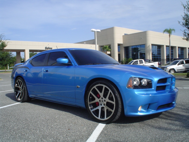 Blue Dodge Charger sedan with silver wheels, 3/4 front view in a parking lot