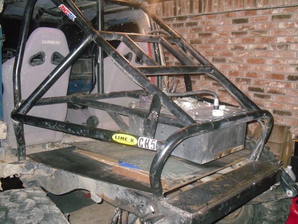 Interior view of a vehicle with a custom roll cage, Corbeau seats, and an auxiliary fuel tank