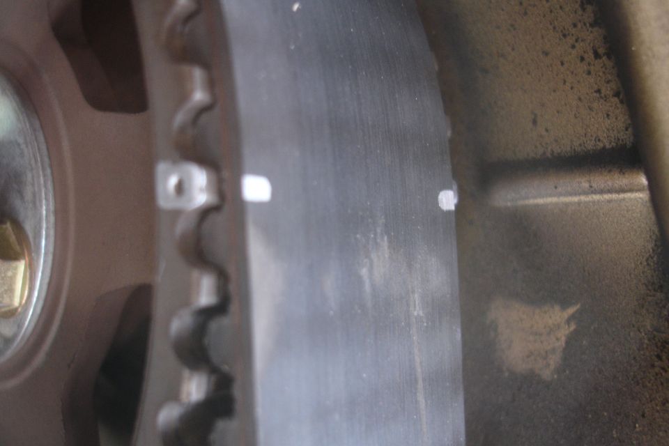 Close-up of a toothed belt and a pulley with white marks on the belt