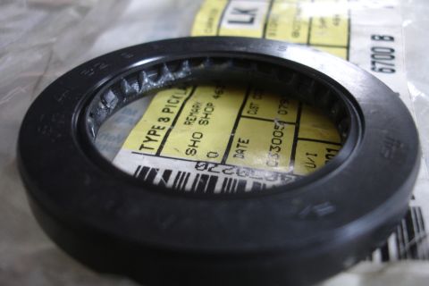 1995 Ford Taurus - A black oil seal is shown with a yellow label that has some text and a barcode.
