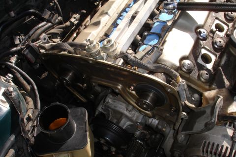 1995 Ford Taurus - Close-up of an engine with the timing cover removed, revealing internal mechanical parts and fuel system components.