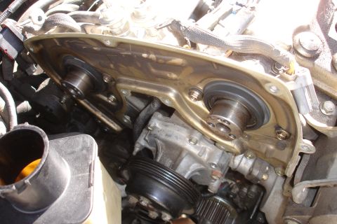 1995 Ford Taurus - Close-up view of engine components, including the timing cover, camshafts, and seals, with some oil residue visible.