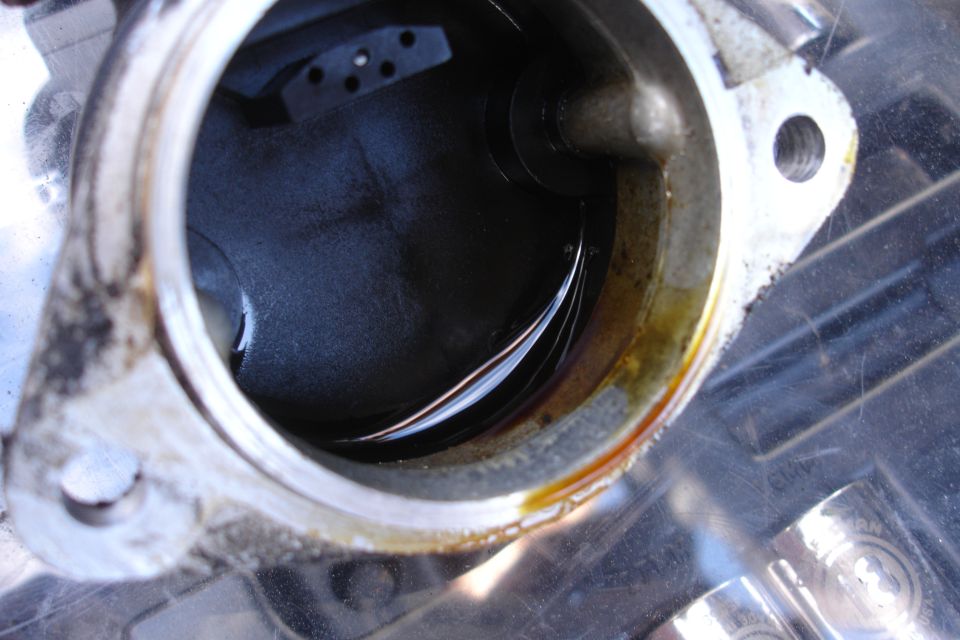 Engine part with oil residue and a circular opening showing dark fluid