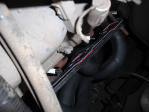 1991 Ford Bronco - Close-up view of an exhaust manifold with a red gasket and spark plugs visible.