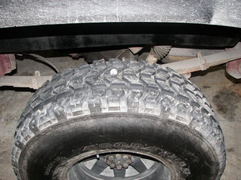 1990 Chevrolet Suburban - Close-up view of a vehicle's rear tire and suspension system, showing leaf springs and shock absorber.