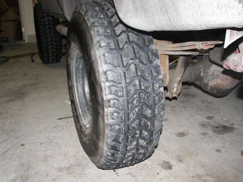 1990 Chevrolet Suburban - The rear tire and suspension components of an unidentified vehicle are visible.