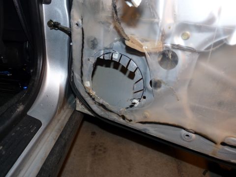2006 Ford E350 - The interior of a car door panel is visible, with a large cutout for a speaker and exposed wiring.