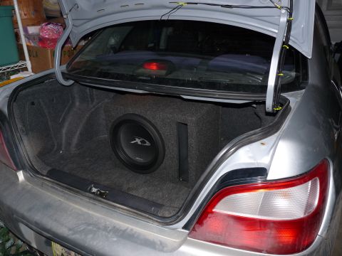 2006 Ford E350 - A large subwoofer is installed in the trunk of a silver sedan.