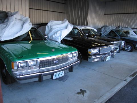 1991 Ford Crown Victoria LTD - Several vehicles are parked inside a metal building, with the front of a green Ford Crown Victoria visible.