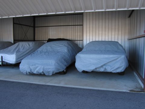 1991 Ford LTD Crown Victoria - Multiple vehicles are stored under protective covers in an indoor facility.