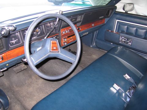1991 Ford LTD Crown Victoria - The interior of a car shows a blue bench seat, dashboard, and steering wheel, suggesting a model from the 1980s.