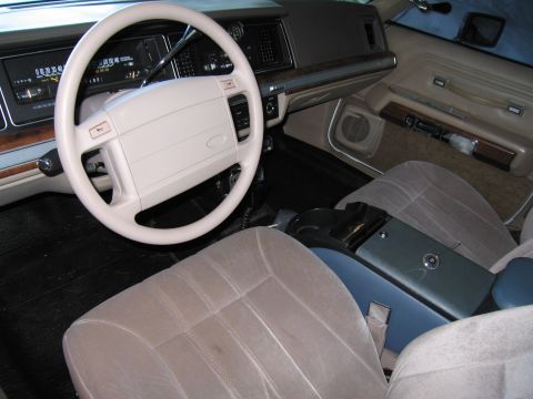 1991 Ford LTD Crown Victoria - The interior of a 1991 Ford Crown Victoria LTD, a tan interior with a large steering wheel and dashboard instrumentation.