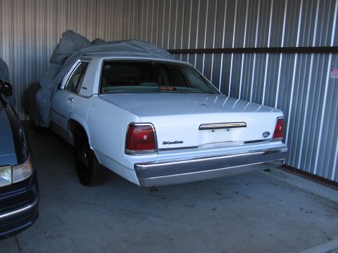 1991 Ford LTD Crown Victoria - The rear of a white 1991 Ford Crown Victoria LTD is shown, with another vehicle partially visible to its left.