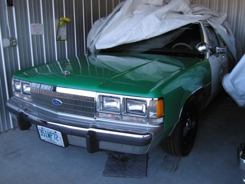 1991 Ford LTD Crown Victoria - A 1991 Ford Crown Victoria LTD police car, seen from the front, is partially covered by a tarp in a garage.