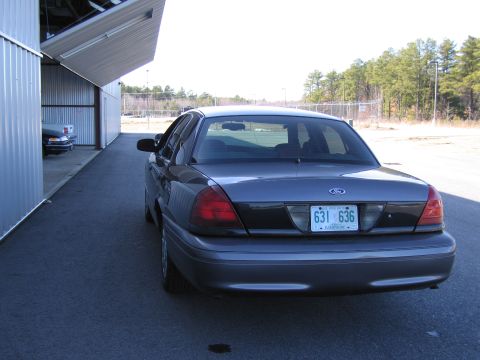 1991 Ford LTD Crown Victoria - A dark gray Ford Crown Victoria is parked outside a metal building. Another car is visible inside the building.