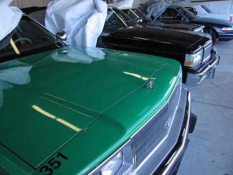 1991 Ford LTD Crown Victoria - A row of cars are parked in a garage, with the front of a green vehicle in the foreground.