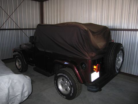 1991 Ford LTD Crown Victoria - A Jeep Wrangler is parked inside a metal garage, partially covered by a tarp.