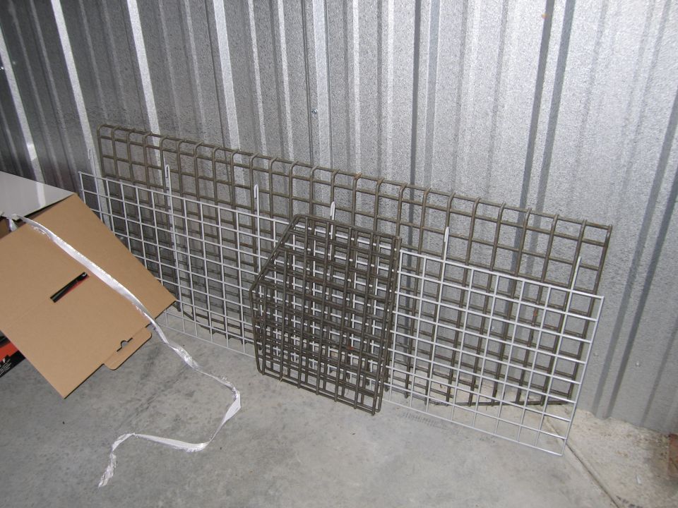 Metal grates and a cardboard box leaning against a corrugated metal wall