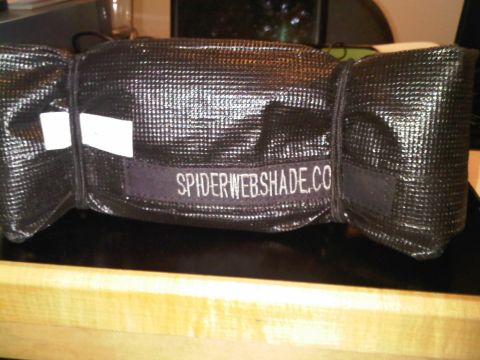 2008 Jeep Wrangler - A rolled-up black sunshade with the text SPIDERWEBSHADE.CO embroidered on it.