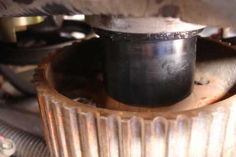 1995 Ford Taurus - Detail of an engine component, a black cylindrical part and a rusty, toothed wheel.