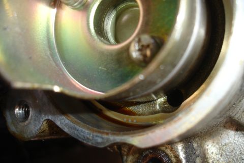 1995 Ford Taurus - Internal view of a mechanical part with visible oil staining and a screw fastener.