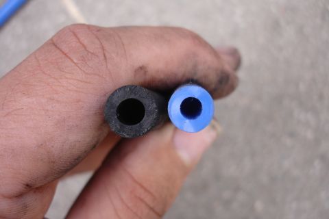 1995 Ford Taurus - A hand holds two hoses, one black and one blue, side-by-side to compare their inner diameters.