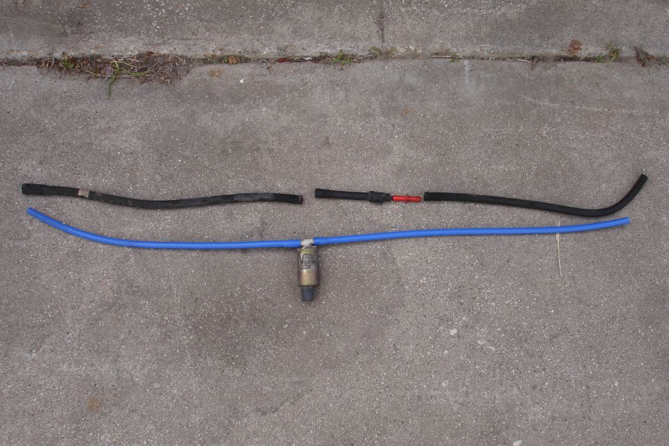 Blue silicone hose with fuel filter and two black hoses on concrete