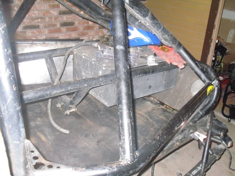 Roll cage inside a vehicle with a fuel tank and blue plastic object