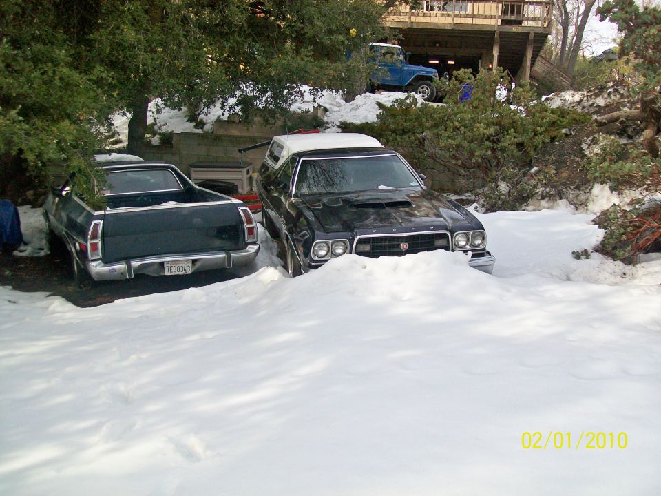 Two dark 1970s Ford Rancheros parked in deep snow, one facing forward with a white roof