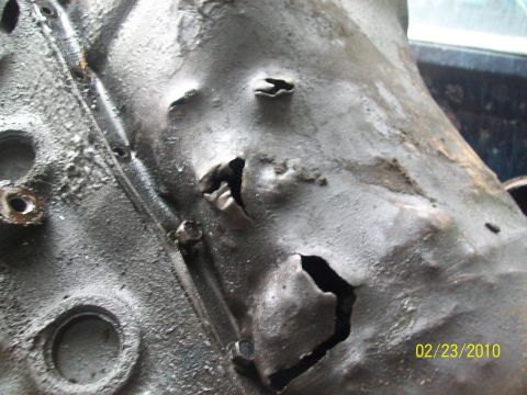 1973 Ford Ranchero - Close-up of a damaged engine block with visible holes and wear.