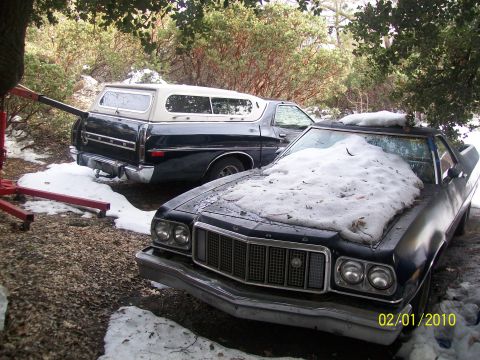1973 Ford Ranchero - Two Ford Rancheros sit in the snow, one with a camper shell on its bed.