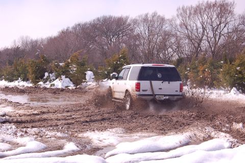 2002 Ford Expedition - White 2002 Ford Expedition navigates a challenging muddy and snowy off-road path.
